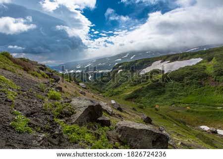 Mountain gorge with green grass and snow on the slopes