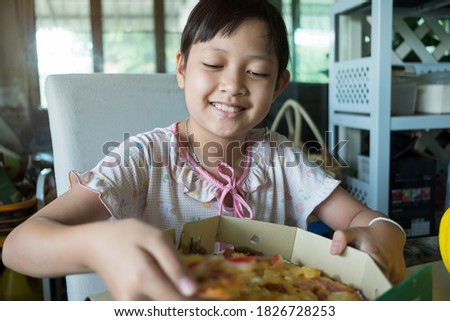 Asian little girl eating pizza at home