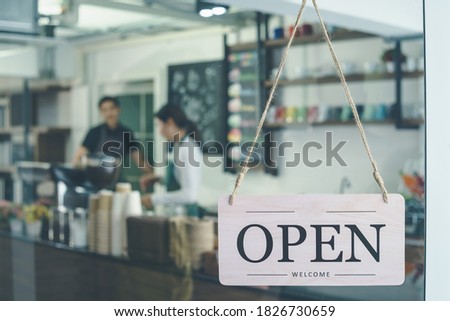 welcome and open sign hung on  front door of  coffee shop. Soft-focus background in restaurants or cafes Business owner and waitresses are working in store. concept Reopen