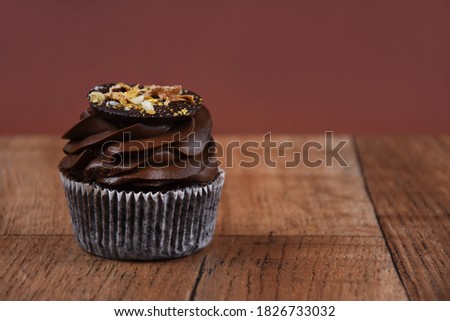 Chocolate cream cupcake on a wooden background stock images. Chocolate cupcake on the table. One delicious cupcake brown frame stock images. Chocolate cupcake brown border with copy space for text