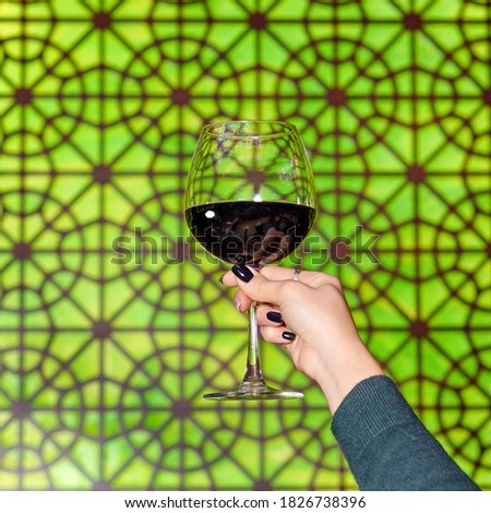 Woman holding a red wine glass with Arabic lantern background