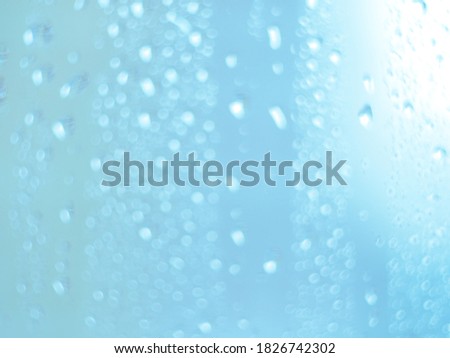 Close focus on water drop on colorful glass. Close focus on water drop on colorful window glass in blue and pink.