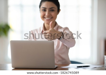 Close up portrait of smiling satisfied indian businesswoman show thumb up recommend online computer program. Happy ethnic female employee use laptop give recommendation to distant work or training. Royalty-Free Stock Photo #1826745089