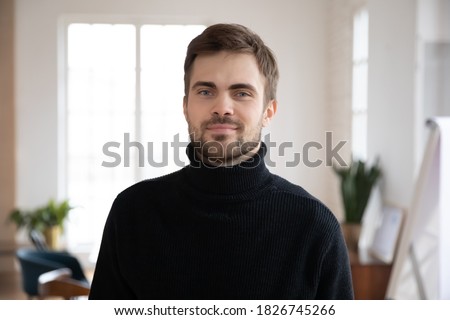 Profile picture of young Caucasian male employee posing in office. Headshot portrait of smiling millennial worker or company intern in workplace workspace. Employment, leadership, hr concept.