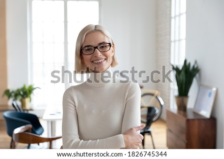 Profile picture of smiling young Caucasian businesswoman in glasses show leadership confidence posing in office. Headshot portrait of happy motivated millennial female employee or worker in eyewear.