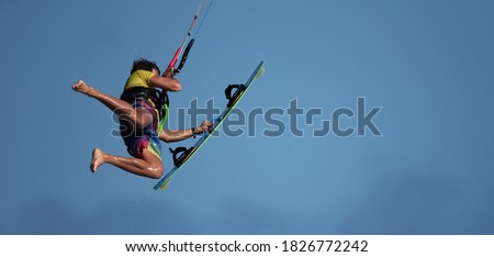 Athletic man jump on kite surf board on a sea waves, kiteboarding action photos