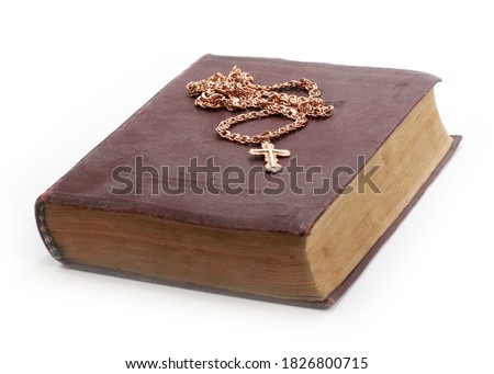 a gold chain with a Christian cross is placed on an old book