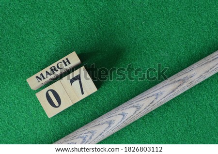 March 7, Number cube With a snooker stick on a green background, snooker table.