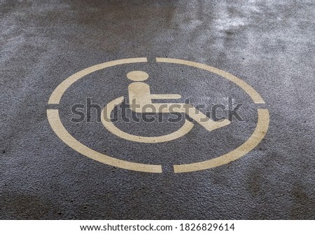 A high angle shot of the handicapped sign painted on the asphalt ground