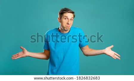 Puzzled male portrait. Careless gesture. Helpless emotion. So what. Doubtful expressive man shrugging looking at camera isolated on blue. Royalty-Free Stock Photo #1826832683