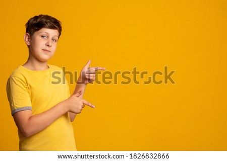 Special offer. Confident child. Information banner. Solution idea. Friendly young boy in yellow t-shirt presenting invisible product pointing at copy space isolated on orange background.