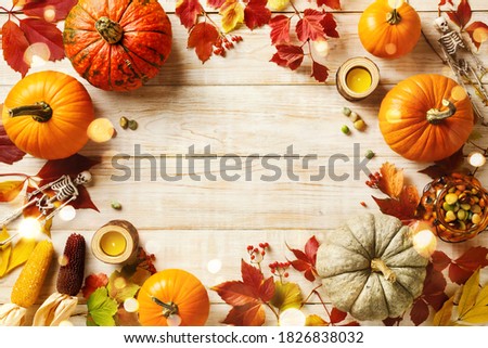 Halloween holiday background with pumpkins, colorful leaves, and lights. Top view. Copy space.