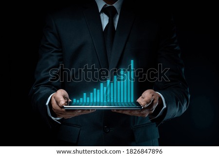 Businessman using tablet planning digital marketing with chart hologram effect.