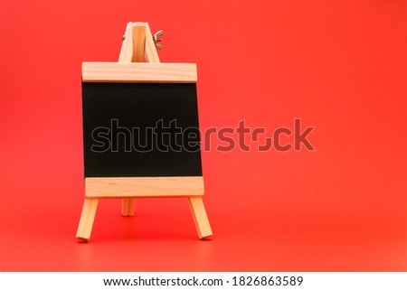 Small easel. Small black board on a red background. Business and education concept.