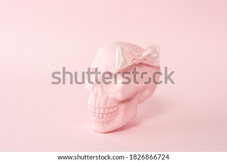 Pink skull with pink bow tie on a pink background. Minimal Halloween spooky girl concept. Royalty-Free Stock Photo #1826866724