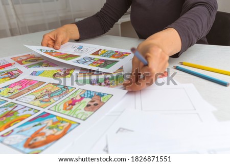 An animator painter draws a color storyboard for a comic book or movie. An illustrator seated at his desk creates a storyboard for a cartoon. 