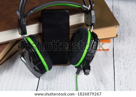 Audiobook concept.Headphones and a smartphone and old books.