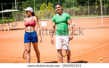 Young athletic woman playing tennis with her coach.