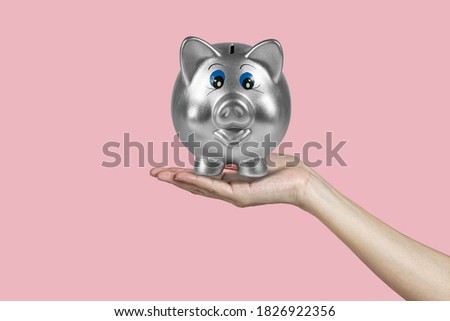 Piggy bank for money safe on woman hand with isolated pink background.