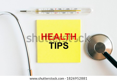 Yellow sticker with the text Health Tips. A thermometer with a phonendoscope on a white background. Can be used as a medical concept photo