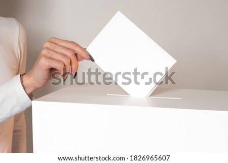 A woman drops a ballot into the ballot box. A woman votes in an election. The concept of elections. Voting in elections. The public referendum. Royalty-Free Stock Photo #1826965607