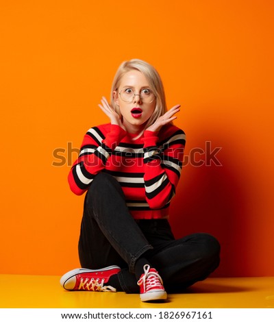 Style hipster woman sitting on a floor near orange background