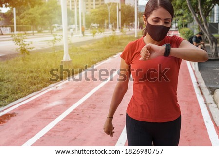 Runner with heart rate monitor sports watch. Woman running and watching her pulse outside in the park
