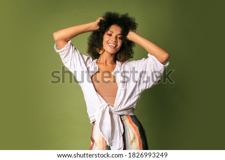 Laighing black female dancing and having fun in studio over green background.  Party mood.  Stylish accessories.
