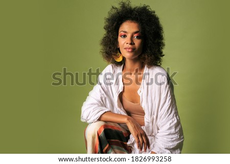 Fashionable african woman in stylish summer outfit posing over green background in studio. 