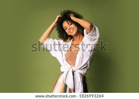 Laighing black female dancing and having fun in studio over green background.  Party mood. Dtylish earrings. 