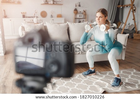 Fitness influencer woman recording video training home on camera. Lifestyle blogger sport and recreation.