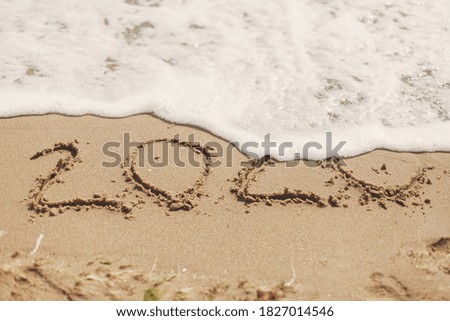 Good bye 2020 ! Wave with foam covering 2020 sign on sandy beach, leaving awful year 2020 behind. Welcoming new year 2021!