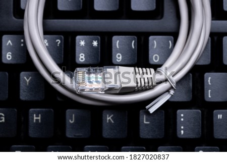network access technology concept. internet lan cable on a black desktop keyboard. above view. studio shot. online forbidden resource conceptual.