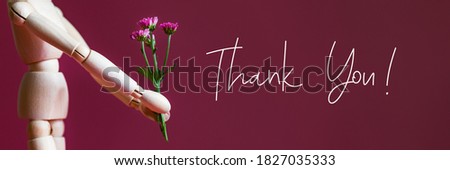 Thank you text and Wooden mannequin is holding tiny purple flowers like chrysanthemum, concept of giving flower bouquet as gratitude