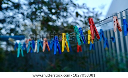 Multicolored clothespins hanging on the rope in evening time. Selective focus.