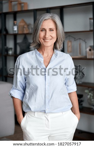 Smiling confident stylish mature middle aged woman stand at home office. Old senior elegant businesswoman, 60s gray-haired lady executive business leader manager looking at camera, vertical portrait. Royalty-Free Stock Photo #1827057917