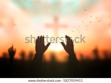 Silhouette christian reaching hands over blurred cross sunset background