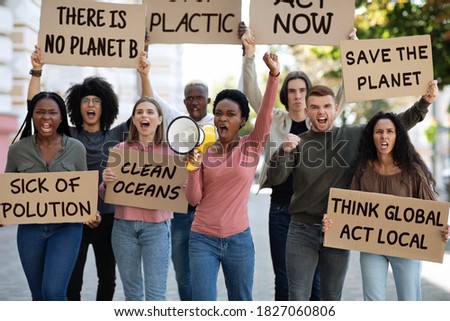 Motivated group of demonstrators striking on the street, fighting for environmental protection. Multiracial group of young people with placards protesting for healthy environment, green planet Royalty-Free Stock Photo #1827060806