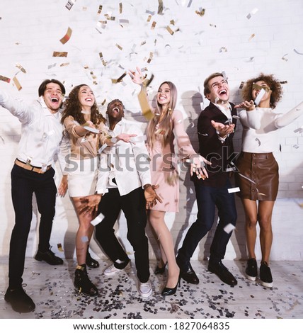 Young People Having Party With Falling Confetti Dancing And Having Fun Standing Indoors. Selective Focus