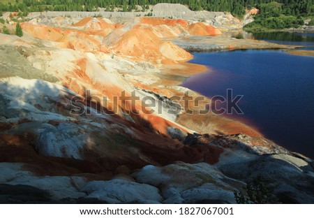 sand and clay quarry with a red lake where refractory clay is mined with a view similar to a Martian landscape like the planet Mars