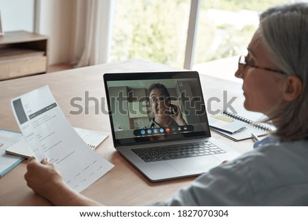 Old female hr reading cv during online job interview by video call. Senior employer checking indian seeker resume talking by social distance remote recruitment chat meeting videoconference on laptop. Royalty-Free Stock Photo #1827070304