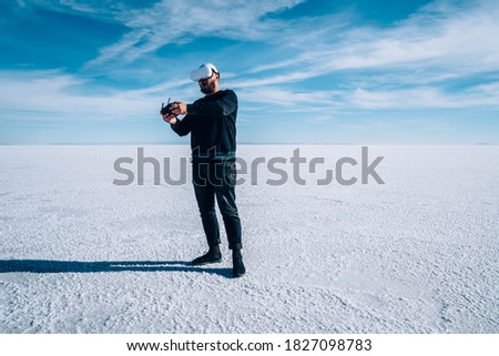 Full length of male tourist in casual outfit using VR goggles and controller while exploring Bonneville Salt Flats during trip in America