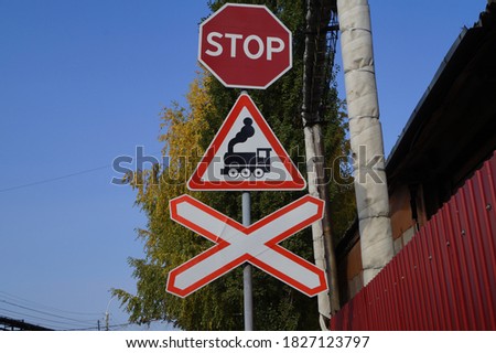 Road sign: "Level crossing". Close-up. Against the background of the blue sky.