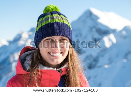Portrait of a woman in a winter hat with a pom-pom on a background of mountain