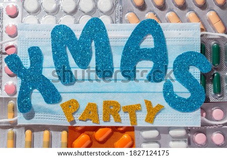 Different medicines: tablets, pills in blister pack, medications drugs on pink background. Medical mask on top. Inscription Xmas party. Close-up photo, copy space, top view.
