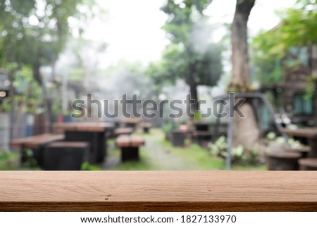 Empty wooden table with blurred background of the park or garden.