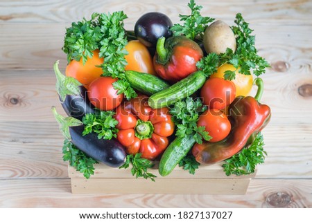 Fresh vegetables in wooden box on wooden background. Selective focus, gorizontal orientation. Harvesting, healthy eating, food delivery concept.