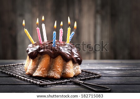 colorful candles on chocolate cake on rustic dark background, Happy Birthday 