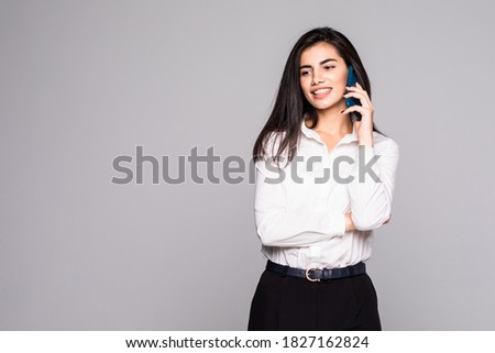 Full length of businesswoman walking talking on mobile phone, isolated on white background