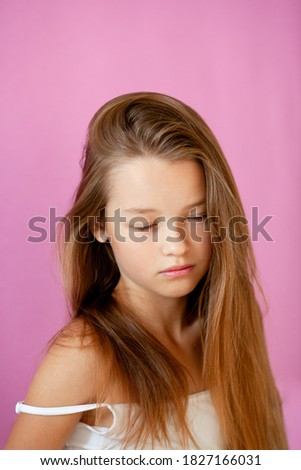 portrait of a gentle 9-year-old long-haired girl against a lilac wall
